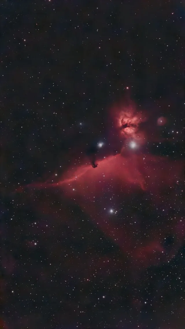 Fotografía astronómica de IC 434 en Orión, con la Nebulosa Cabeza de Caballo recortada sobre una extensa emisión rojiza, la Nebulosa de la Llama y Alnitak brillando entre numerosas estrellas.